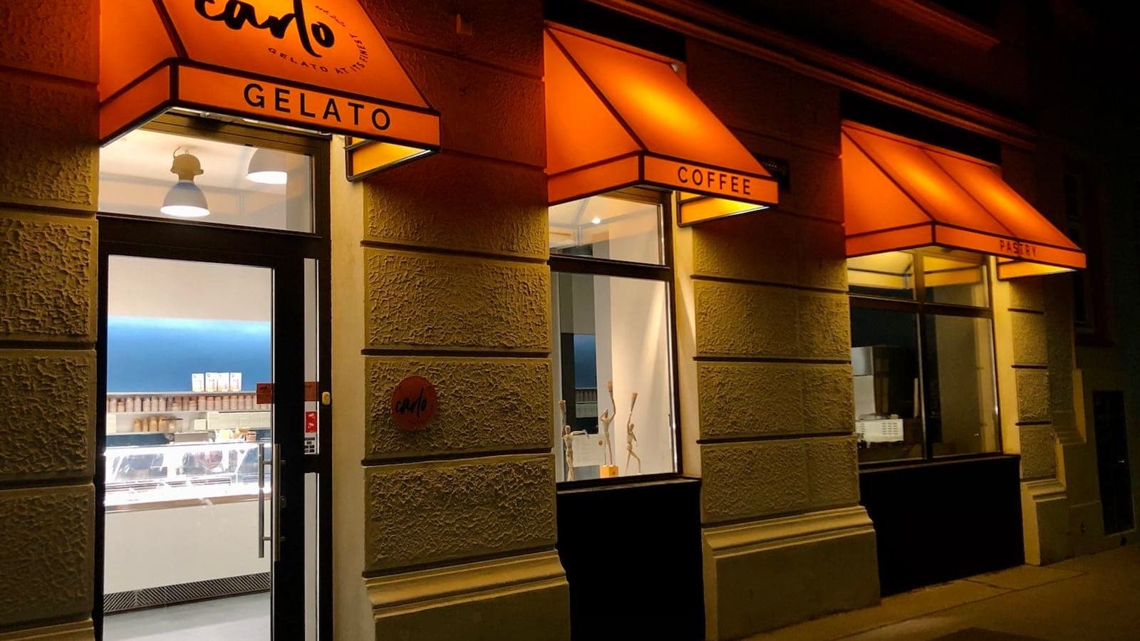 The shop front at night, glowing under lit orange awnings